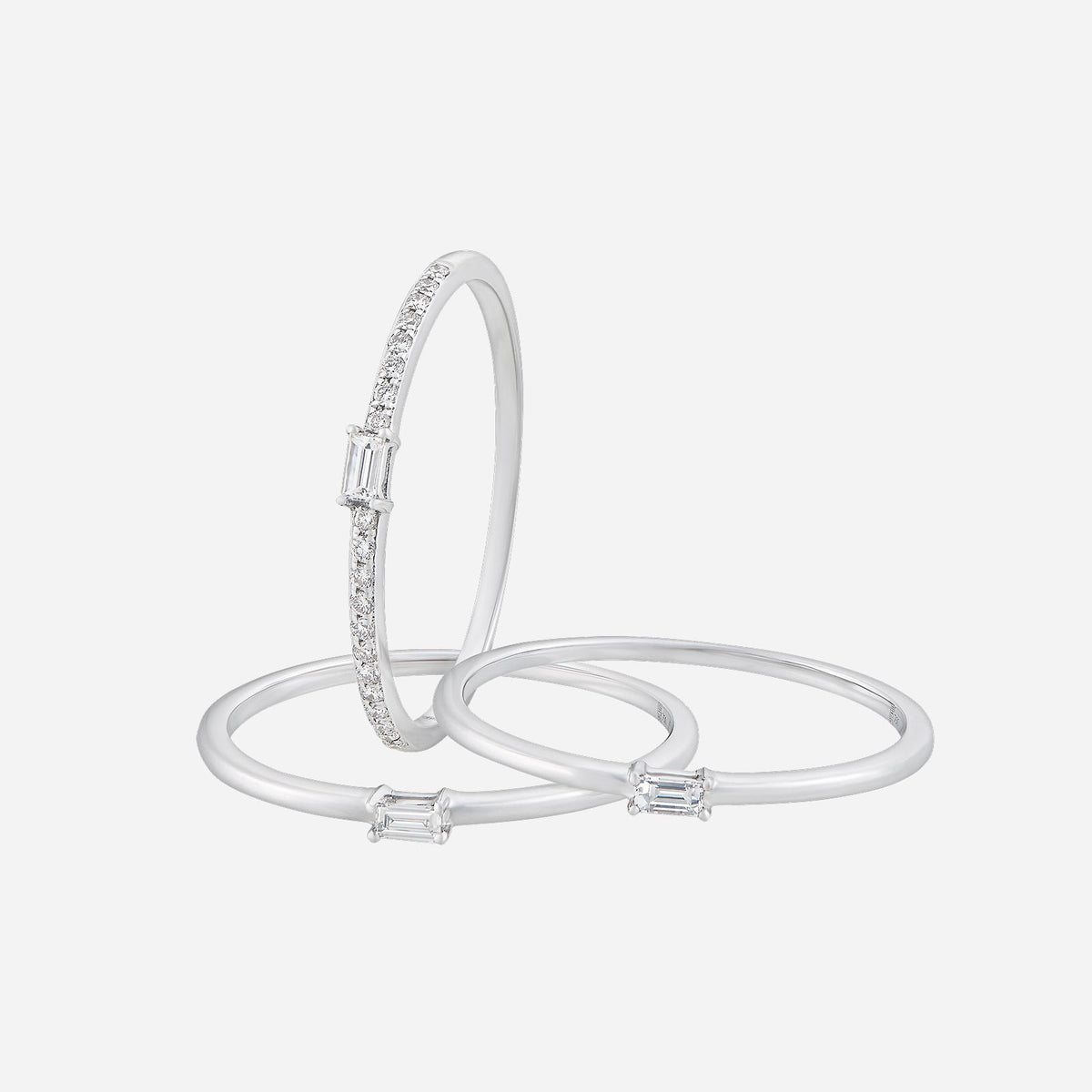 elegant white gold trio line diamond ring featuring emerald-cut and pavé diamonds, showcasing modern elegance and style.
