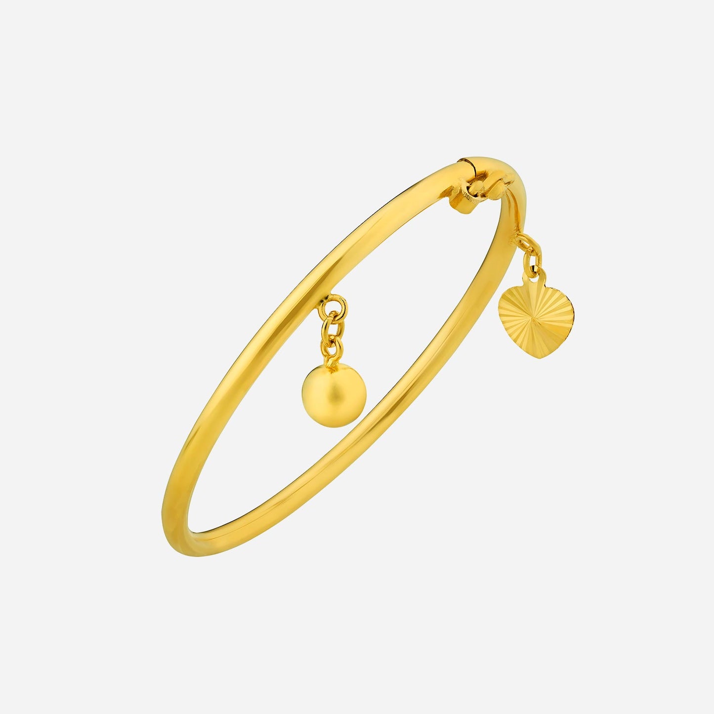 22k yellow gold baby bangle featuring smooth finish and a dangling ball and heart charm for a playful touch.