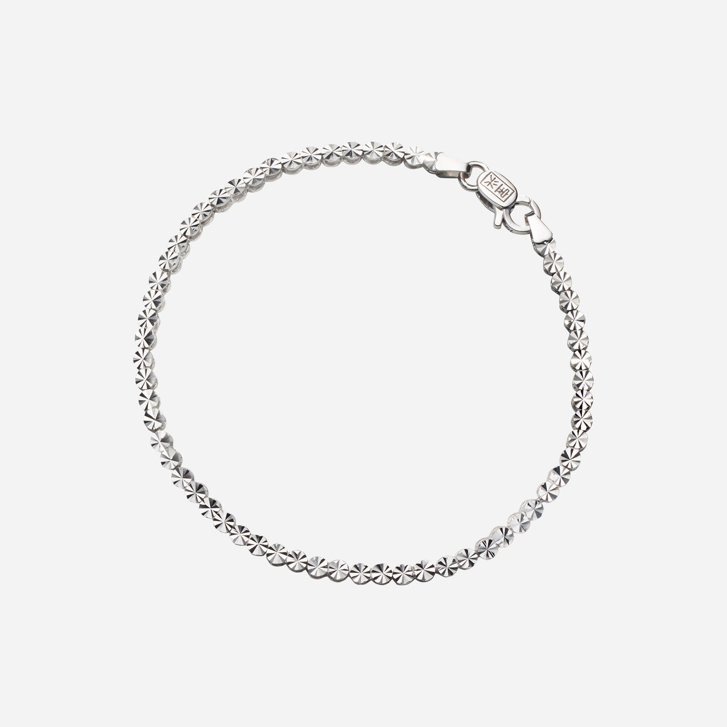 textured bracelet in 18k white gold with flat circular motifs and secure clasp design.
