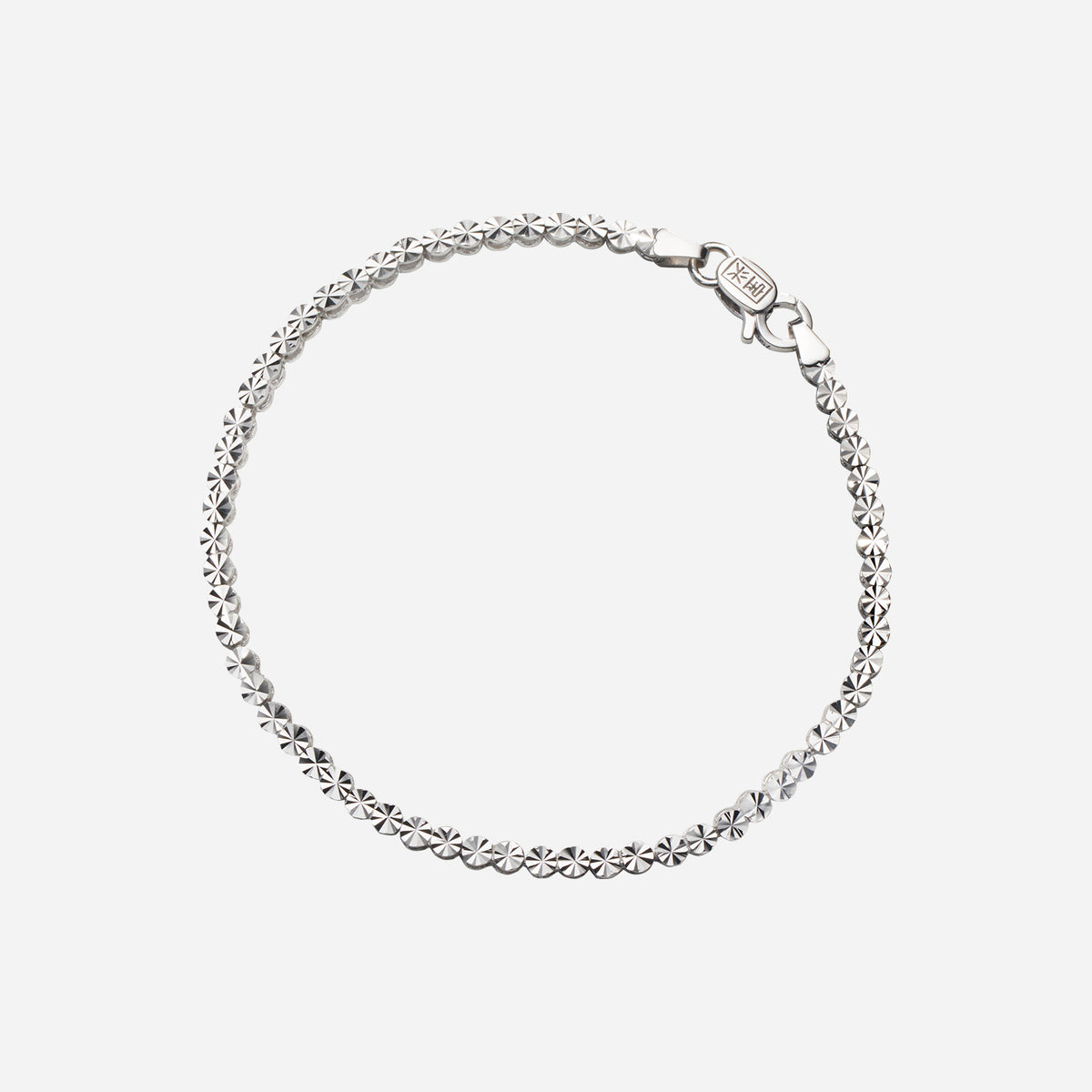textured bracelet in 18k white gold featuring flat circular motifs with intricate cuts. elegant and classic design.