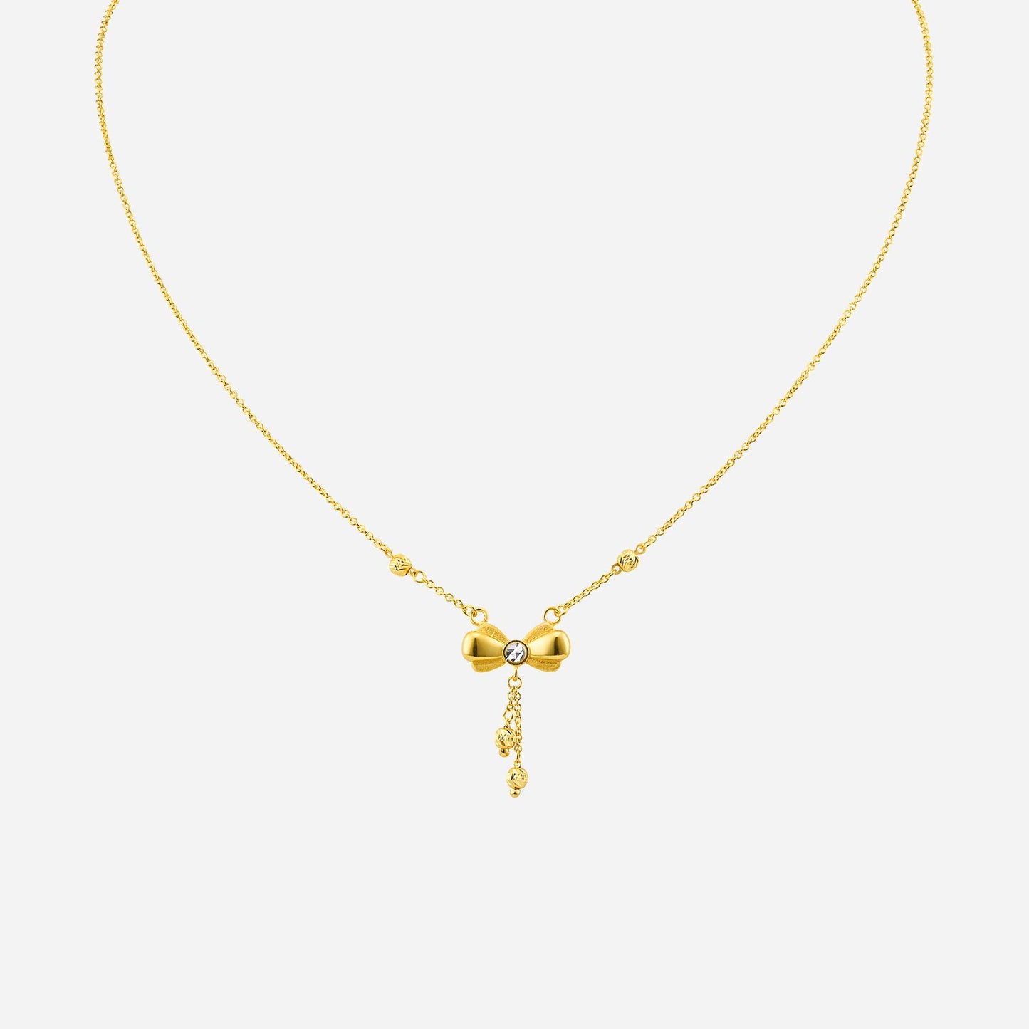 bow ribbon necklace in 22k yellow white gold with a central gemstone and decorative chains. elegant and auspicious design.