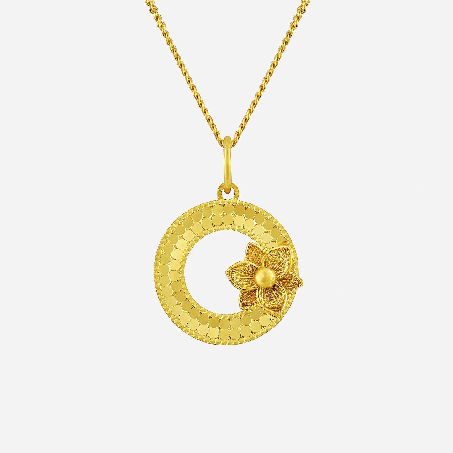glittering circular flower pendant in 22k yellow gold with textured circle and floral design. chain sold separately.
