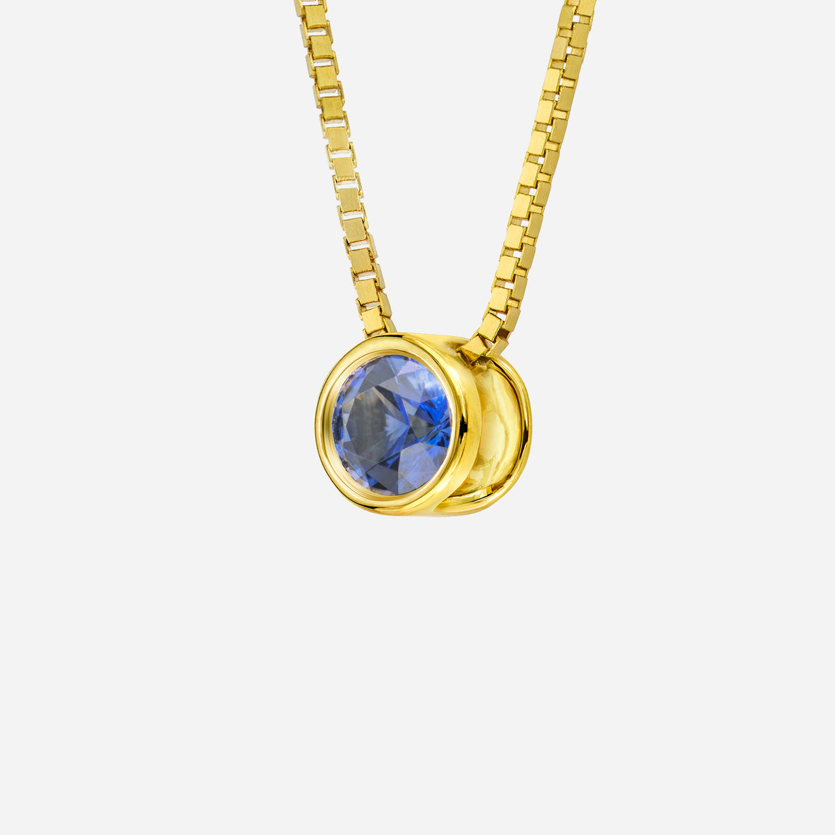 18k yellow gold pendant featuring a round blue sapphire gemstone in a sleek, modern design. chain not included.