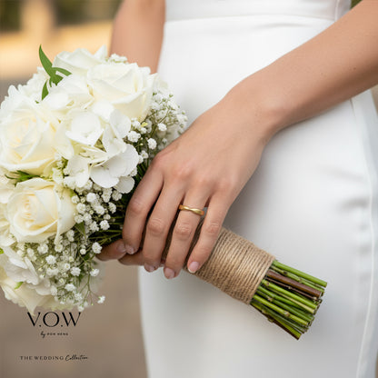 Timeless Love Band in 22K champagne gold with a sleek design, worn on a bride’s hand holding a bouquet.