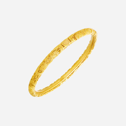 Auspicious 24K yellow gold bangle with intricate peony and cloud motifs, symbolising wealth and harmony.