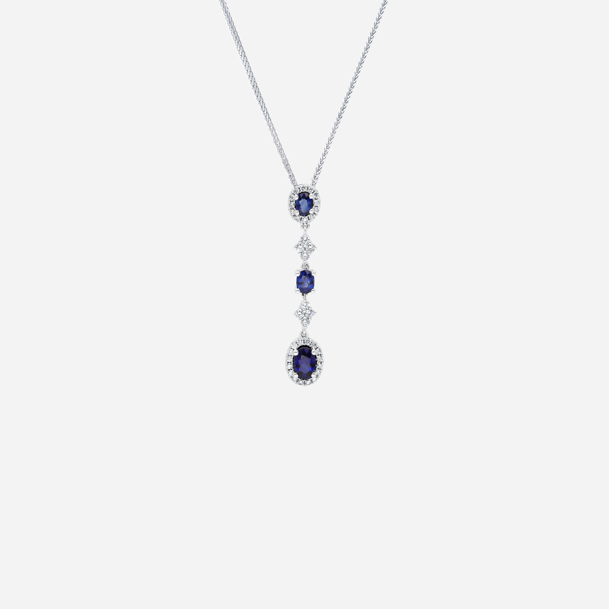 Blue sapphire and diamond pendant in 18K white gold with oval sapphires and diamond halos for elegant fluid movement.