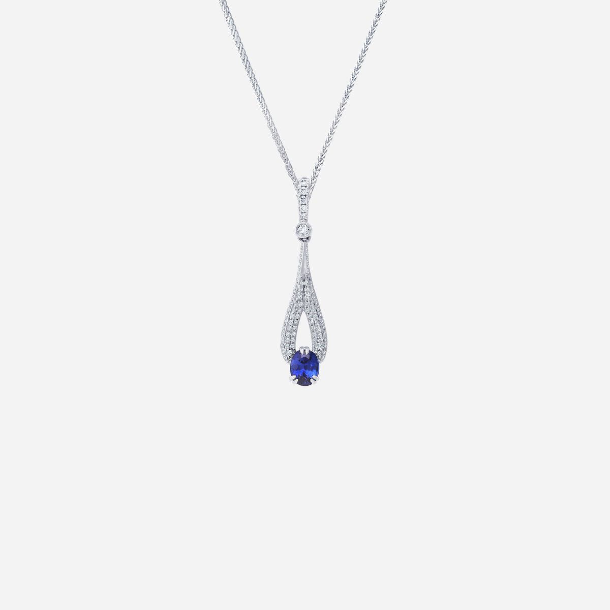 Blue sapphire pendant in 18K white gold, surrounded by pavé-set diamonds in elegant elongated design.