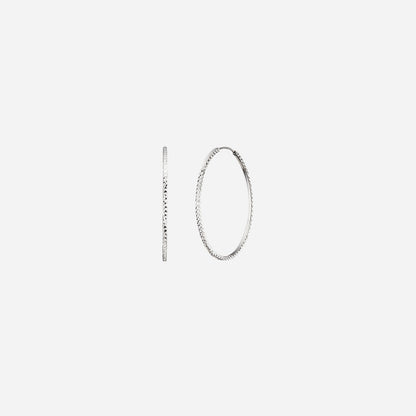 Textured huggie earrings in 18K white gold featuring a classic hoop design with intricate cut detailing.